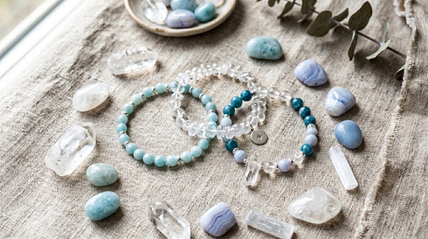 Photorealistic flat-lay of crystal bracelets and gemstones in airy blue tones