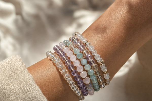 Stacked crystal bead bracelets on a wrist in natural daylight