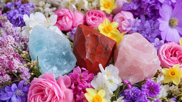 Aquamarine, red jasper, and rose quartz crystals scattered among spring flowers