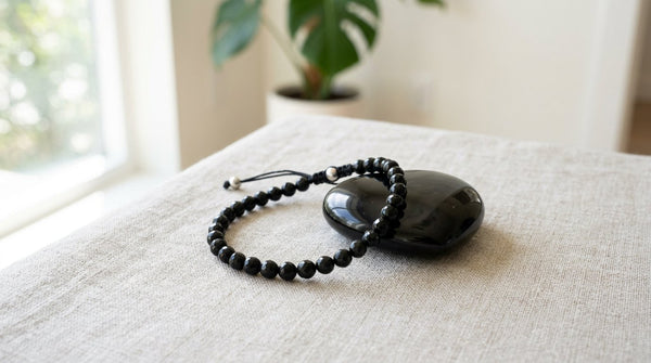 Black tourmaline bracelet and black obsidian stone on a neutral background