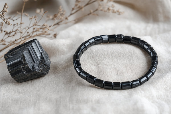 Black tourmaline bracelet with a raw black tourmaline stone on neutral fabric.