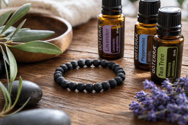 Black lava stone bracelet on wooden surface with essential oil bottles — spa aesthetic