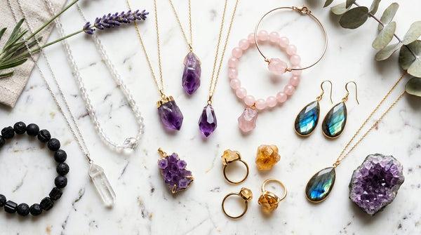 Assorted healing crystal jewelry collection including amethyst, rose quartz, and citrine pieces on white marble