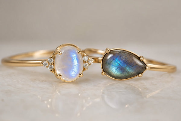 Moonstone and labradorite gemstone rings side by side showing blue glow and iridescent flash
