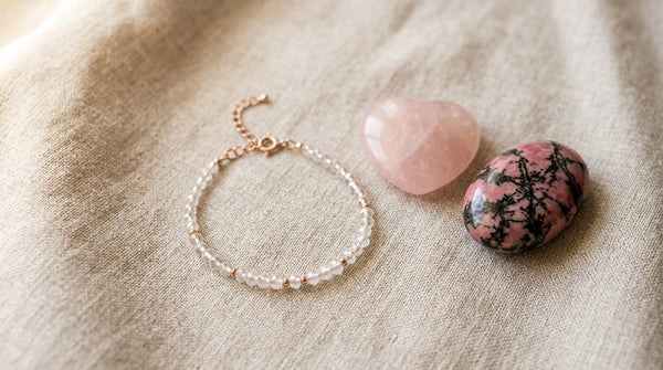 Rose quartz and rhodonite stones next to a crystal bracelet